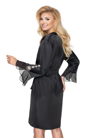 A woman with long blonde hair smiles while looking over her shoulder. She is gracefully donning the Irall Cleopatra Dressing Gown by Irall, a black satin robe featuring sheer ruffled cuffs and decorative buttons on the sleeves. The delicate satin tie at the waist enhances the shiny, elegant appearance of this sophisticated dressing gown.