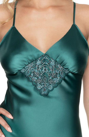 A close-up photo of a person wearing an Irall Emerald III Nightdress in dark green with spaghetti straps. The nightdress, exuding exclusivity, showcases intricate lace detailing in the center of the chest area. The person's left hand rests on their hip, exposing part of their arm.