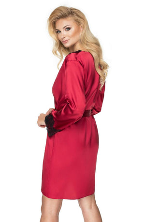 A woman with long, wavy blonde hair is posing in an Irall Juniper Burgundy Dressing Gown featuring elegant black lace cuffs. She is turned slightly to the side, looking over her shoulder with a subtle smile against a plain white background.