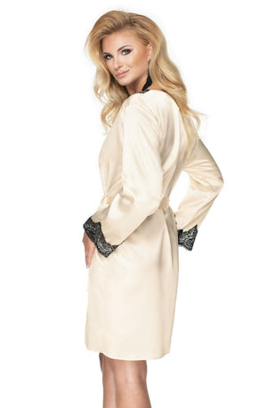 A blonde woman wearing the Irall Juniper Cream Dressing Gown from Irall, featuring elegant black lace cuffs, poses with her hands in the robe's pockets. She has long, wavy hair and is looking over her left shoulder.