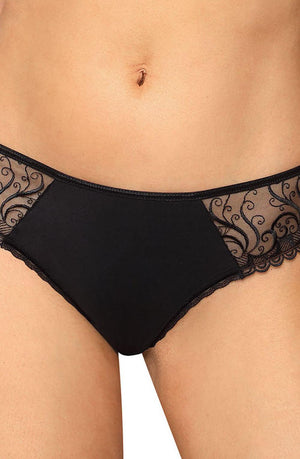 A person wearing the Roza Anuk Thong Black, designed by Roza, is seen from the waist to the upper thigh. The underwear features sheer lace panels with intricate floral patterns on the sides, scalloped edges along the leg openings, and is made from stretch material. The person's skin tone is visible through the lace.