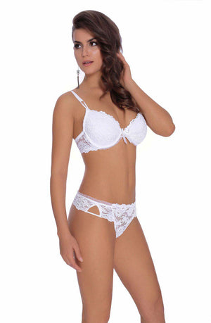 A woman with long, wavy hair poses against a plain white background wearing a white lace bra and the Roza Carmen White Thong by Roza. She is looking to the side with one hand touching her hair, and she wears a single, dangling earring.