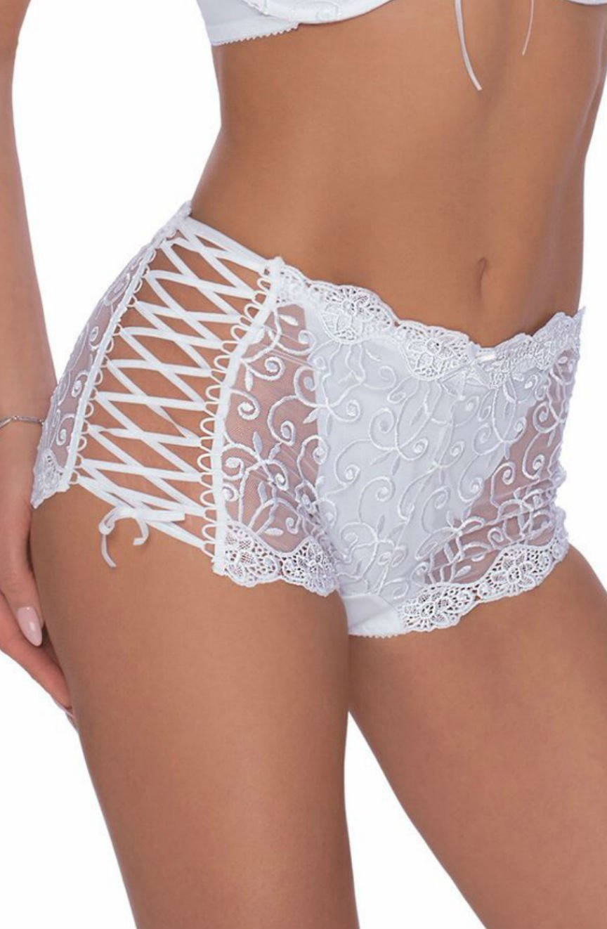 A woman wearing the Roza Ginewra Short White lingerie set from the Roza brand. The high-waisted panties feature intricate lace patterns, sheer side panels with crisscross lace-up details, and scalloped edges. The matching push-up bra has a delicate lace design and thin straps, perfect for bridal wear. The background is plain.