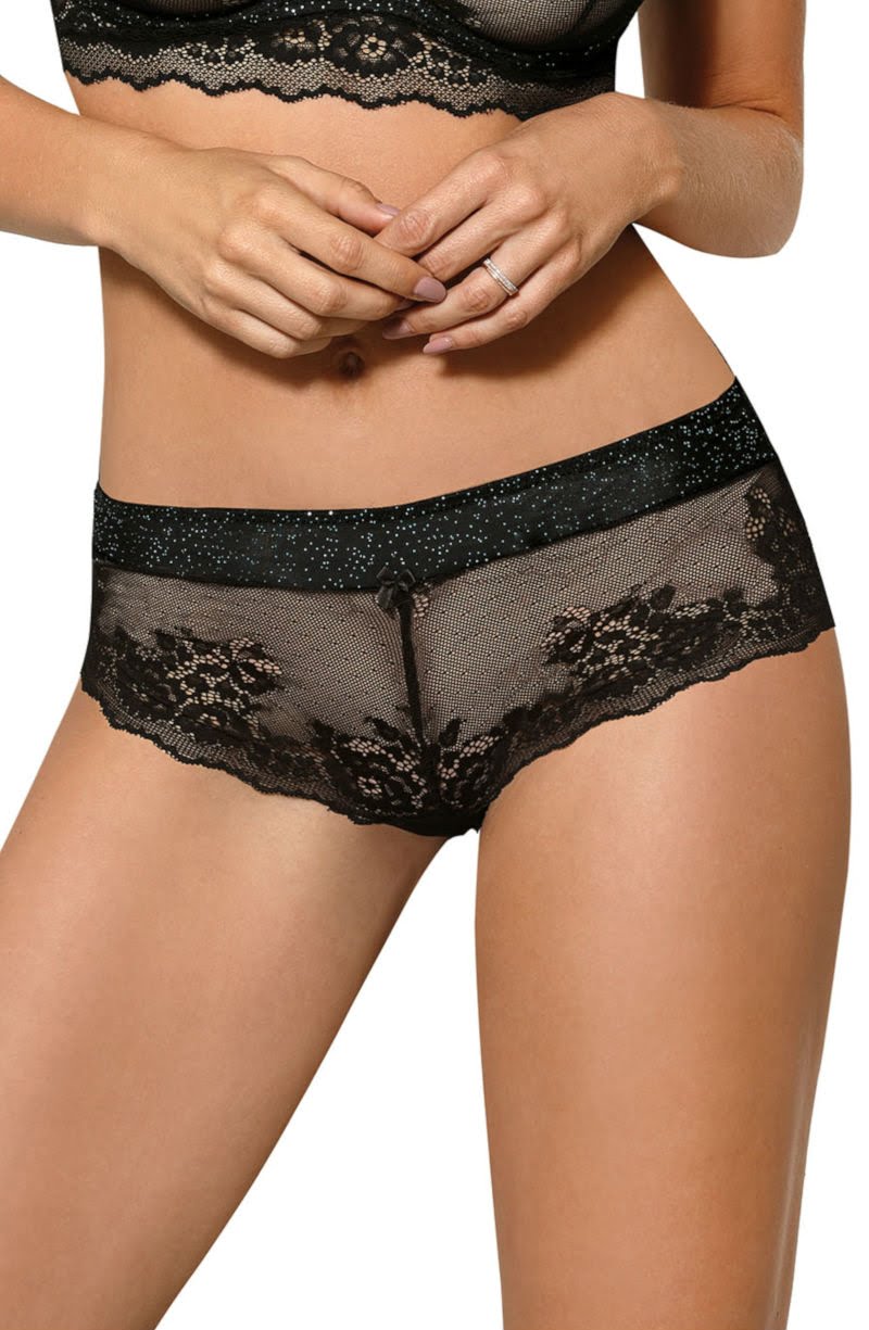 A woman is wearing the Roza Kena Black Brief, a lacy lingerie set by Roza that includes seductive thongs. The design boasts intricate floral lace patterns and sheer fabric elements. She has a ring on her left hand. The image focuses on her torso and midsection, emphasizing the exquisite details of the lingerie.