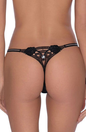 A close-up image shows the lower back and buttocks of a person wearing the Roza Lea Thong Black, a detailed thong from Roza adorned with black lace, embroidered roses, and a small white jewel at the center. The thong features thin side straps.