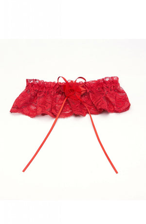 The Shirley Of Hollywood 18 Garter Red by Shirley of Hollywood is a red lace leg garter adorned with a small rose and ribbon bow streamers at the center. Designed with a delicate, frilled lace pattern, it exudes an elegant and romantic appearance. The garter is displayed flat against a plain white background.